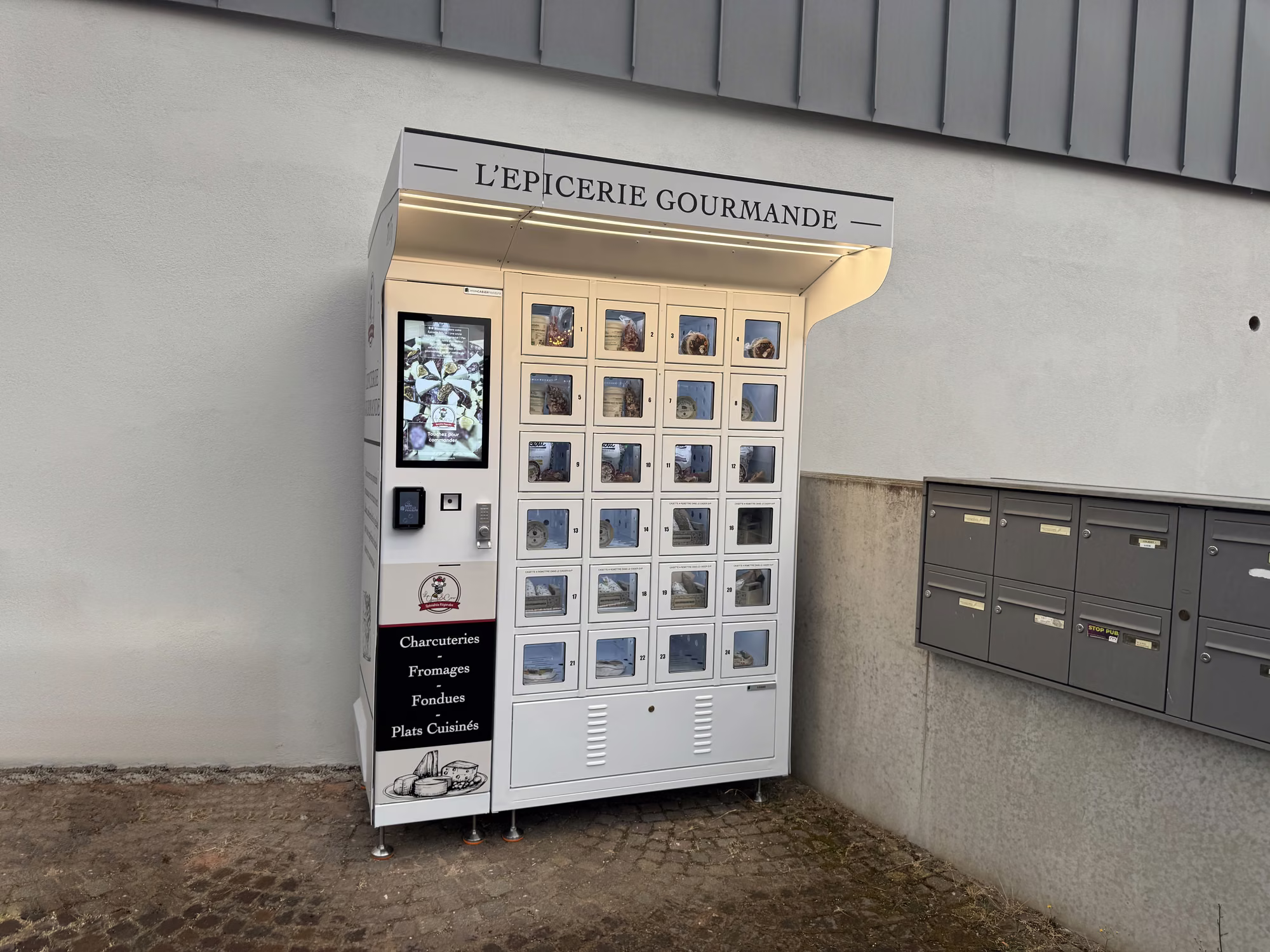 Minimalistische overkapping van L'Épicerie Gourmande in Sausheim, met kluisjeskast en bestelzuil